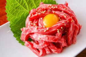 牛ユッケに使用される部位はどこ？美味しい食べ方や注意点も！ 実は・・「牛ユッケ」食した事がありません。。　ぶっちゃけ「生レバー」も貧血が出た時に食べた程度です。。　私の中で生肉=危険と言う固定観念を持っているのもあるかもしれません。　だけど私の周りの友人達はみな、「あんな美味しいものを食べないなんて・・」 と言うのです。 今回は「牛ユッケ」について、苦手意識を失くしてみよう！と思い調べてみました。 ① ユッケは禁止？ 2011年4月に牛ユッケ集団食中毒事件により、多くの人々が食中毒の被害に遭いました。中には腸管性出血性大腸菌O-111によって亡くなられた方もいるほどで悲惨な事件でした。 これによって、焼肉店などでは牛のレバーを刺身で提供することが禁止されましたが、全面的に法律で禁止となったのは牛のレバーでした。 問題のきっかけとなった牛のユッケに関しては、条件付きで提供することが認められているそうです。　条件とは、生食用の食肉専門の設備を備えた衛生的な場所の確保が必要であることだそう。 この条件をクリアしているお店に関しては許可証があるので目印になるそうです。 この許可証があったら、より安心して食べられますね。 生食用の牛肉として人気のユッケ！焼肉とは違いあっさりして贅沢なお肉の１つだから、 これからも、安心して食べたいですよね。 ② 牛ユッケに使用される部位はどこ？ そもそもユッケとは、モンゴルのタルタル・ステーキが朝鮮半島に伝わり、「ユッケ」となりました。ユッケは韓国語のユック（肉）とフェ（刺身）が合わさった言葉で、韓国では馬肉を食す習慣がなかったので、牛肉が代用されていたそうです。 ユッケに使う牛肉は　主に赤身肉のモモ肉が使われる事が多いそうです。 一般的に牛の内モモ肉がよく使用されるようです。 モモ肉は主に腰からお尻・太ももの内側・外側の4つの部位で形成されていて、内モモは 赤身で柔らかく濃厚な味があるのが特徴です。 ローストビーフ用にも使われている部位だそうで、モモ肉にサシ(霜降り)が入るのは上質なお肉の証なんだそうです。 ローストビーフは大好きでめちゃめちゃ食べるのだけど、ユッケも同じ部位だとは・・ 友人たちが美味しいと言うのも頷けました。。 ③ 美味しい食べ方や注意点！ さてユッケの美味しい食べ方としては、焼肉店では基本的に、皿の中に入っているものを（味はすでに付いているので）全部グチャグチャに混ぜてそのまま食べましょう。梨やリンゴ、きゅうりなどの千切りが添えられている場合は混ぜずに、それをつまみながら食べると良いそうです。 最近では、インターネット通販でも購入が可能になっているらしく、いつでも好きな時に食べられるのは嬉しいですね！冷蔵や冷凍での販売もお店によって取り扱っているみたいです。ただ、注意しておきたいポイントとしては、「食べきりサイズで個包装」である事。 一度で食べ切れるサイズで、新鮮なうちに食べ切れるような商品を選ぶ事が大事ですよね。、あと、やはり生のお肉を食べる時は食虫毒の可能性も頭に入れる必要があります。。 小さなお子さんやご年配の方、体が弱っている状態で食べるのは気をつけましょう。 生肉＝危険という固定観念を持っていた私ですが、生の牛肉ユッケは食べられる！という事、国の基準をクリアしたお店であれば安心して食べられる！という事が分かりました。 お肉大好き人間の私。。今まで敬遠していたユッケだけど、この機会にチャレンジしてみようかな。ま、手始めにユッケビビンバにして食べてみようか笑